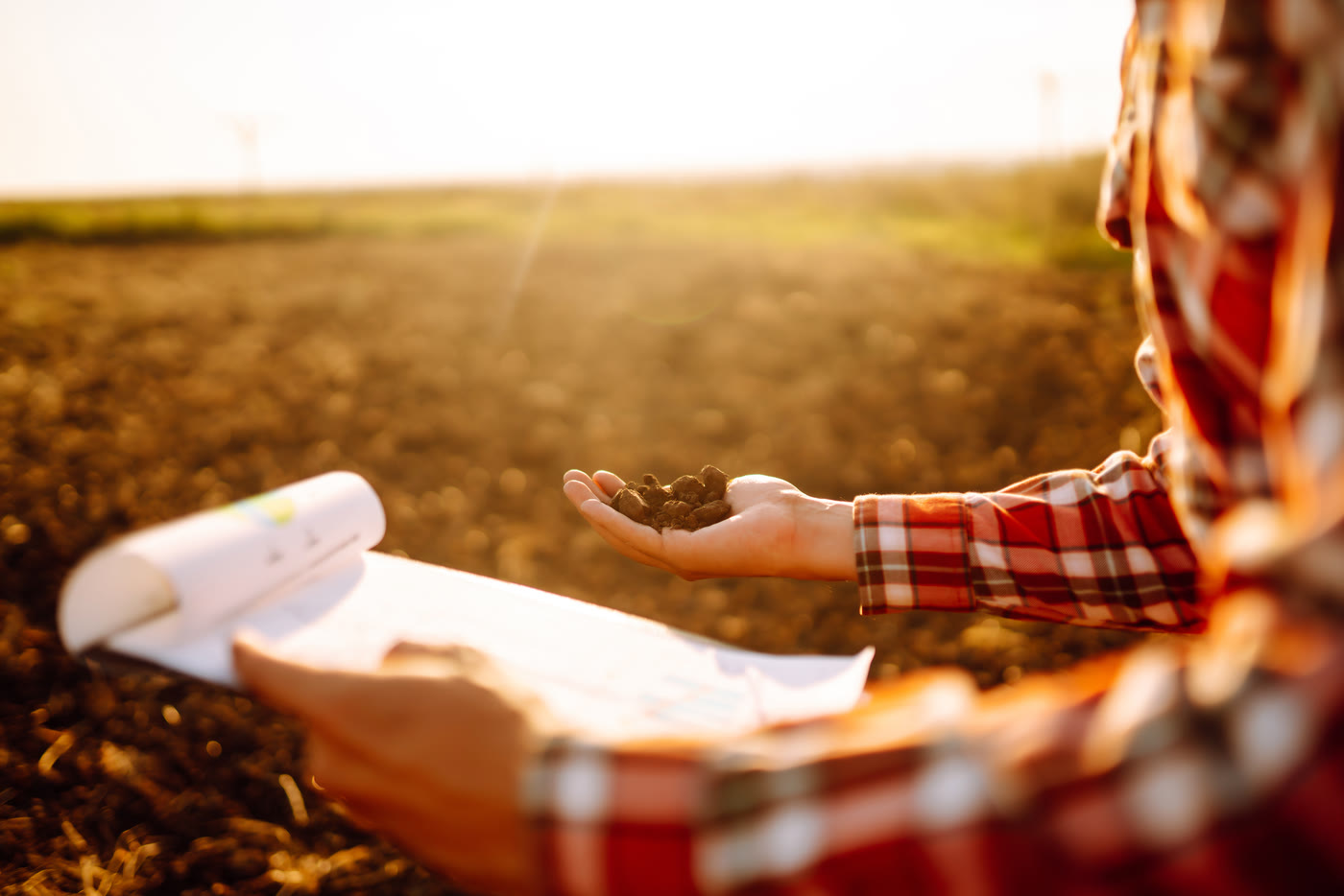 A farmer examining a handful of soil at sunset