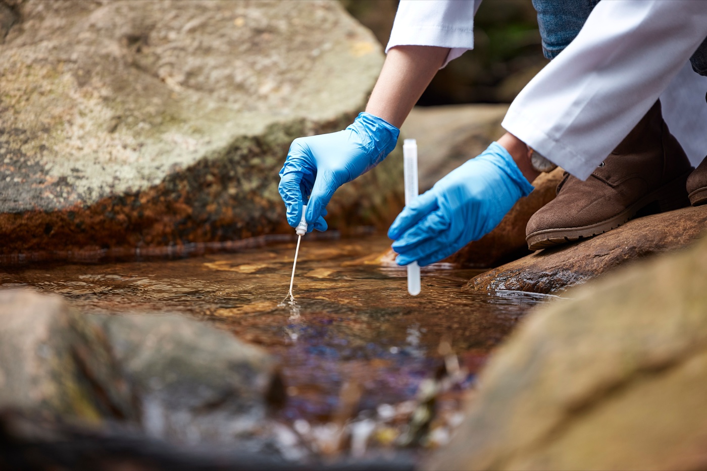 Scientist sampling water from a rocky stream